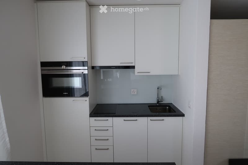 Modern kitchen with white cabinets, stainless steel oven, sink, and faucet.