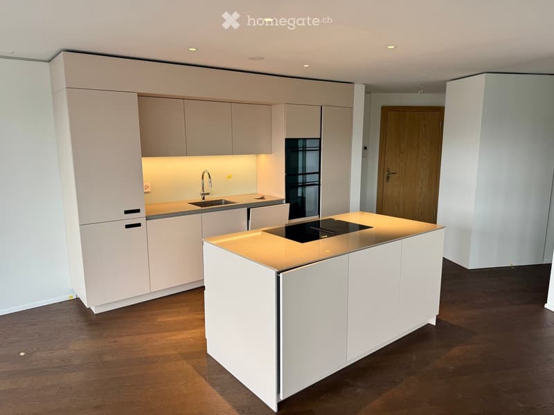 Modern kitchen with white cabinets, a central island, and a sink area. The island features a built-in induction cooktop and ample storage space.