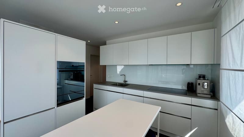 Modern kitchen with white cabinets, stainless steel appliances, and a sleek countertop.