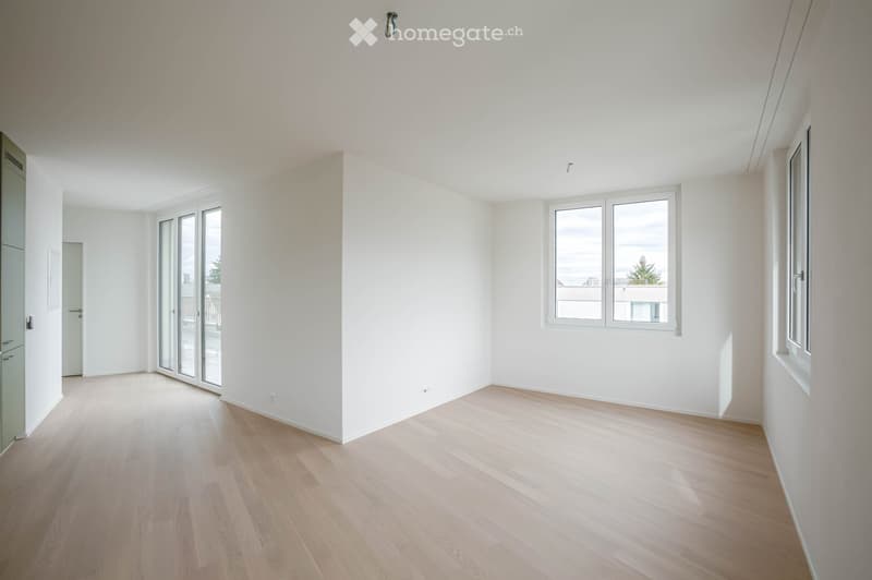 Empty room with light wooden flooring, white walls, and large windows allowing natural light. The space is unfurnished, with no visible furniture or equipment.