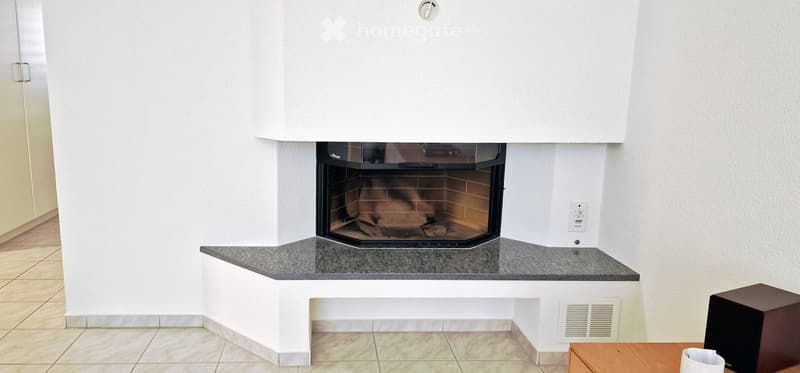 Modern fireplace with a built-in bench, surrounded by white walls and tiled flooring.