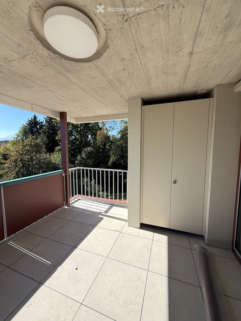 Balcony with tiled floor, metal railing, and a view of trees and mountains. The ceiling has a circular skylight.