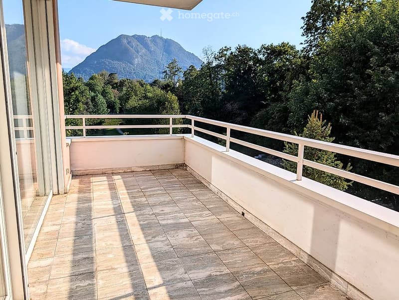 Balcony with tiled floor, white railing, and scenic mountain view.