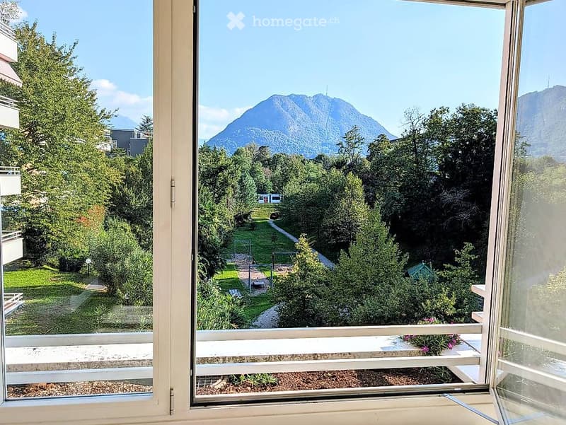 Balcony with a scenic mountain view, surrounded by trees and a well-maintained garden area.