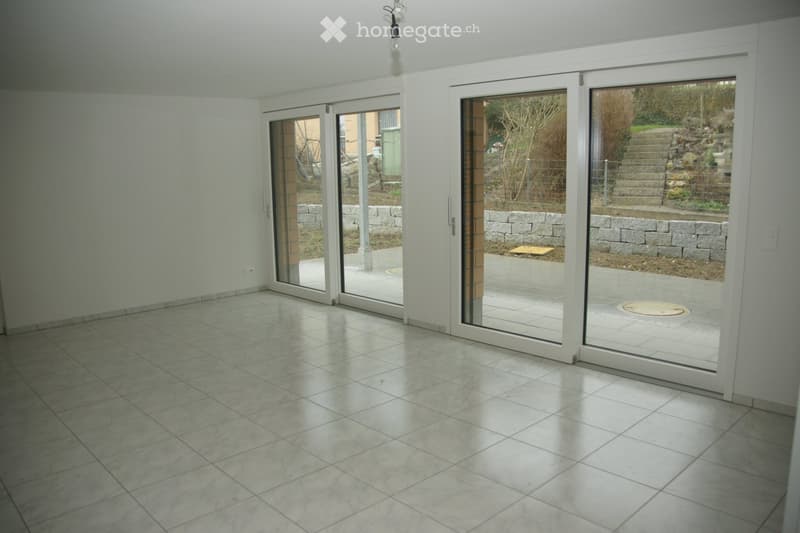 Empty room with large sliding glass doors leading to a patio area, tiled floor, and white walls.