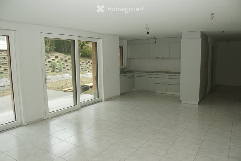 Empty kitchen with tiled floor, white cabinets, and sliding glass doors leading to an outdoor area.