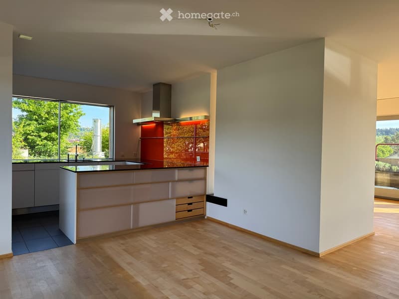 Kitchen. Modern kitchen with light-colored cabinets, a central island, and large windows offering a view of greenery outside.