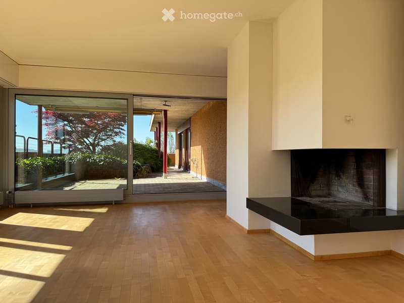 Living Room. Modern living room with light wooden flooring, large glass doors leading to a patio, and a built-in fireplace.