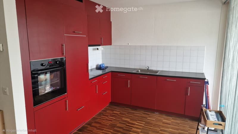 Modern kitchen with red cabinets, black countertop, stainless steel sink, and built-in oven. Wooden flooring and white tiled backsplash.