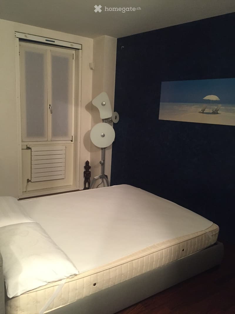 Bedroom with a white bed, a modern lamp, and a picture frame on the wall.