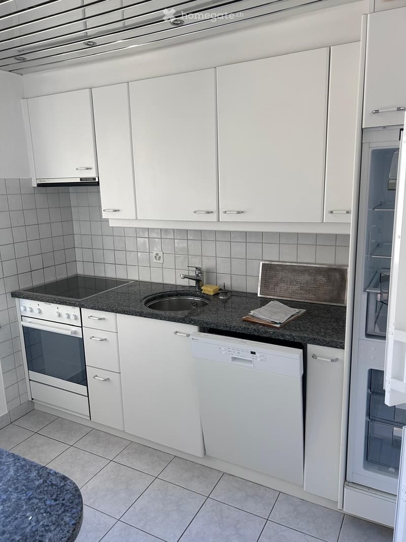 Modern kitchen with white cabinets, granite countertop, stainless steel sink, oven, dishwasher, and refrigerator.