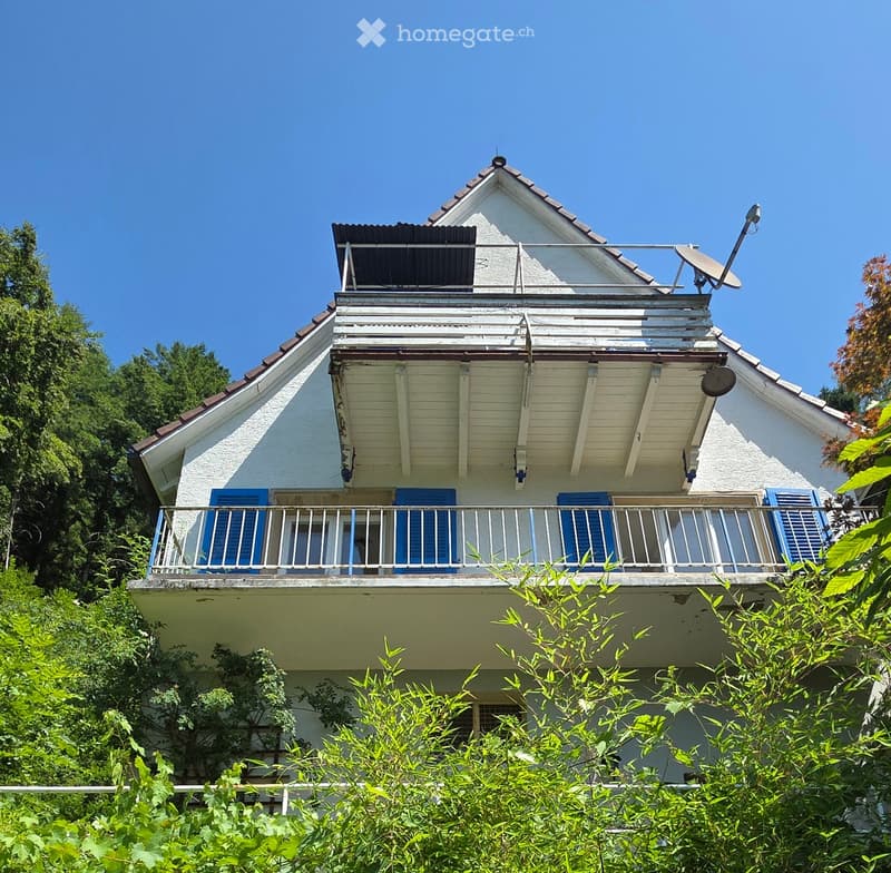 Two-story house with white exterior, blue shutters, and a balcony on the upper level.
