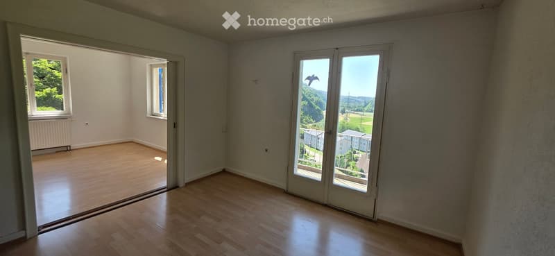Empty room with wooden flooring, large windows, and a view of the landscape outside.