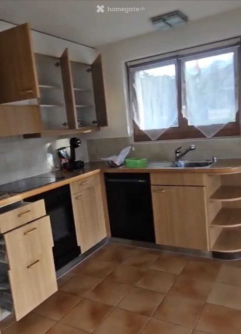 A modern kitchen with light wooden cabinets, a stainless steel sink, a dishwasher, and a coffee maker on the counter.