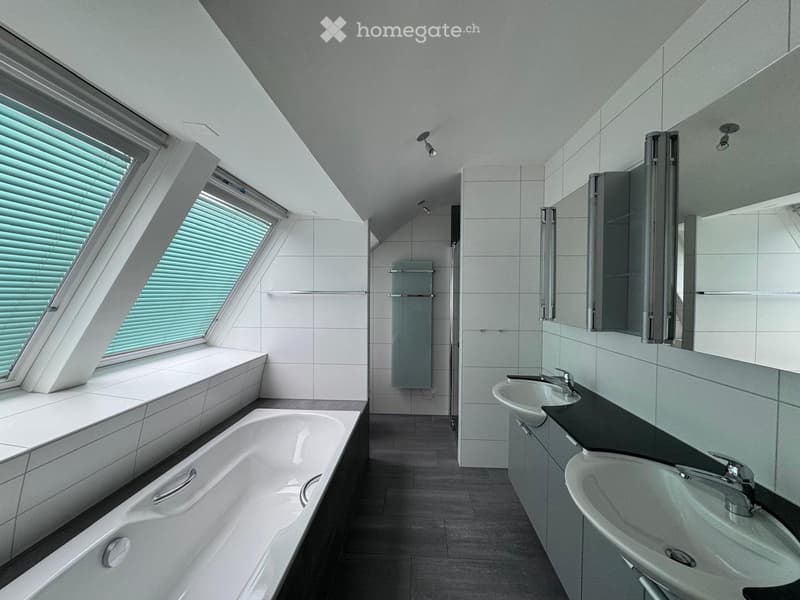 Modern bathroom with a large window, bathtub, double sink, mirror, and radiator.