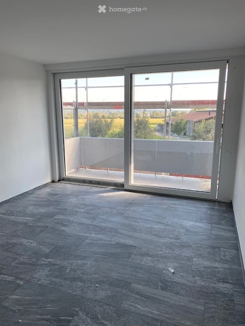 Sliding doors leading to a balcony, concrete floor, white walls