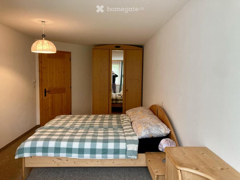bedroom with wooden bed, wooden cabinet, wooden door, wooden floor, white walls, lamp