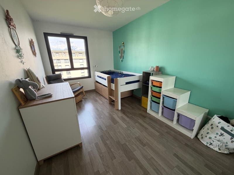 Bright, modern bedroom with a lofted twin-sized bed, a small desk with a chair, a storage unit with colorful bins, and a cozy reading nook with a bean bag chair.