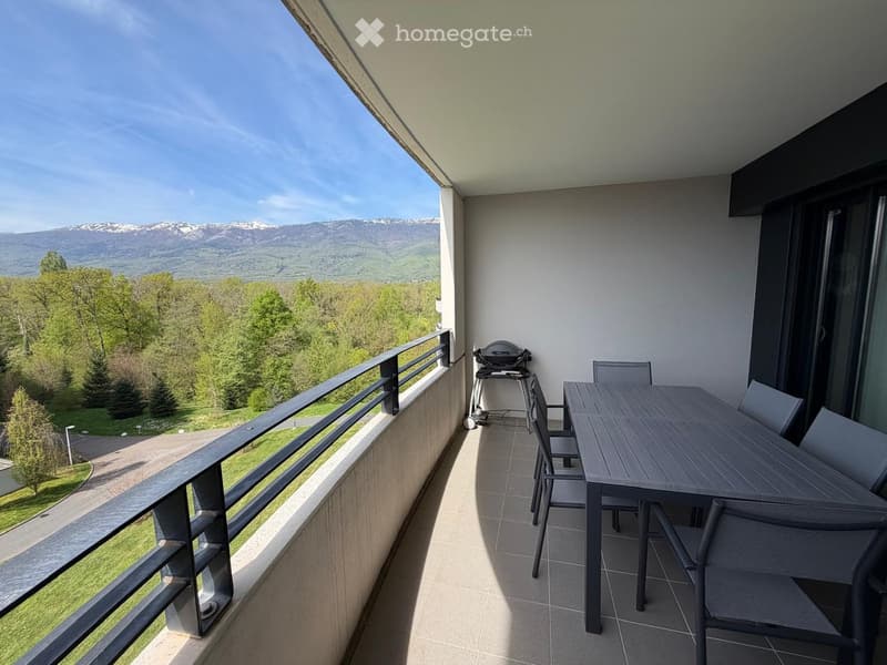 Balcony with a table, chairs, and a grill, offering a scenic mountain and forest view.
