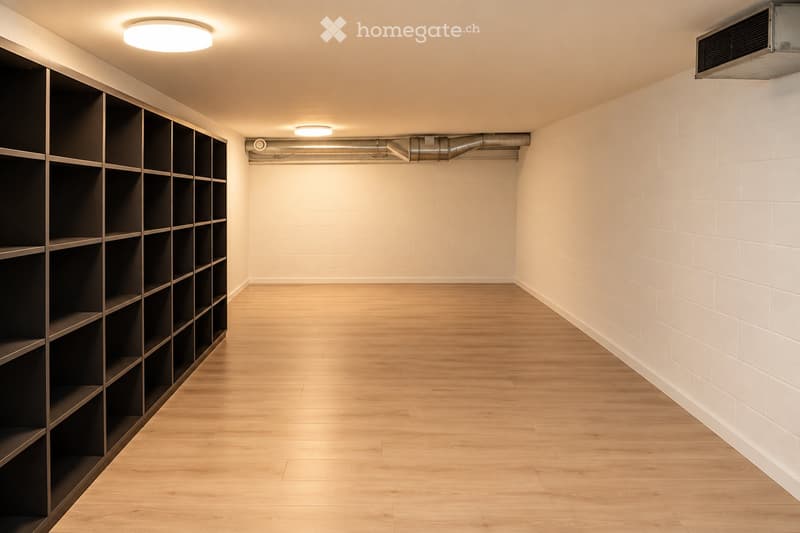 Empty hallway with wooden flooring, white brick walls, built-in shelving unit on one side, and recessed lighting.