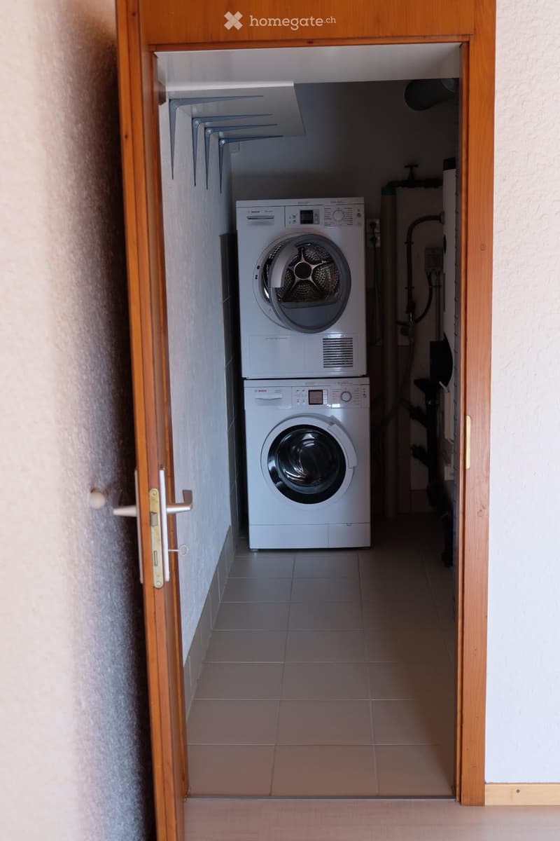 A small, tiled bathroom with a white Bosch washing machine and a white Bosch dishwasher stacked vertically.