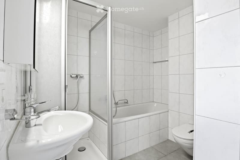 modern bathroom with white tiles, bathtub, shower, sink, toilet