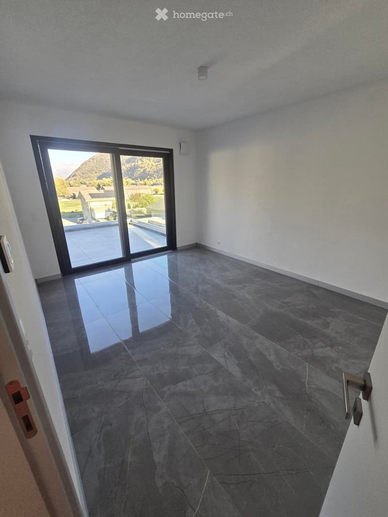 Empty room with dark grey tiled floor, large sliding glass door leading to outdoor area with mountain view.