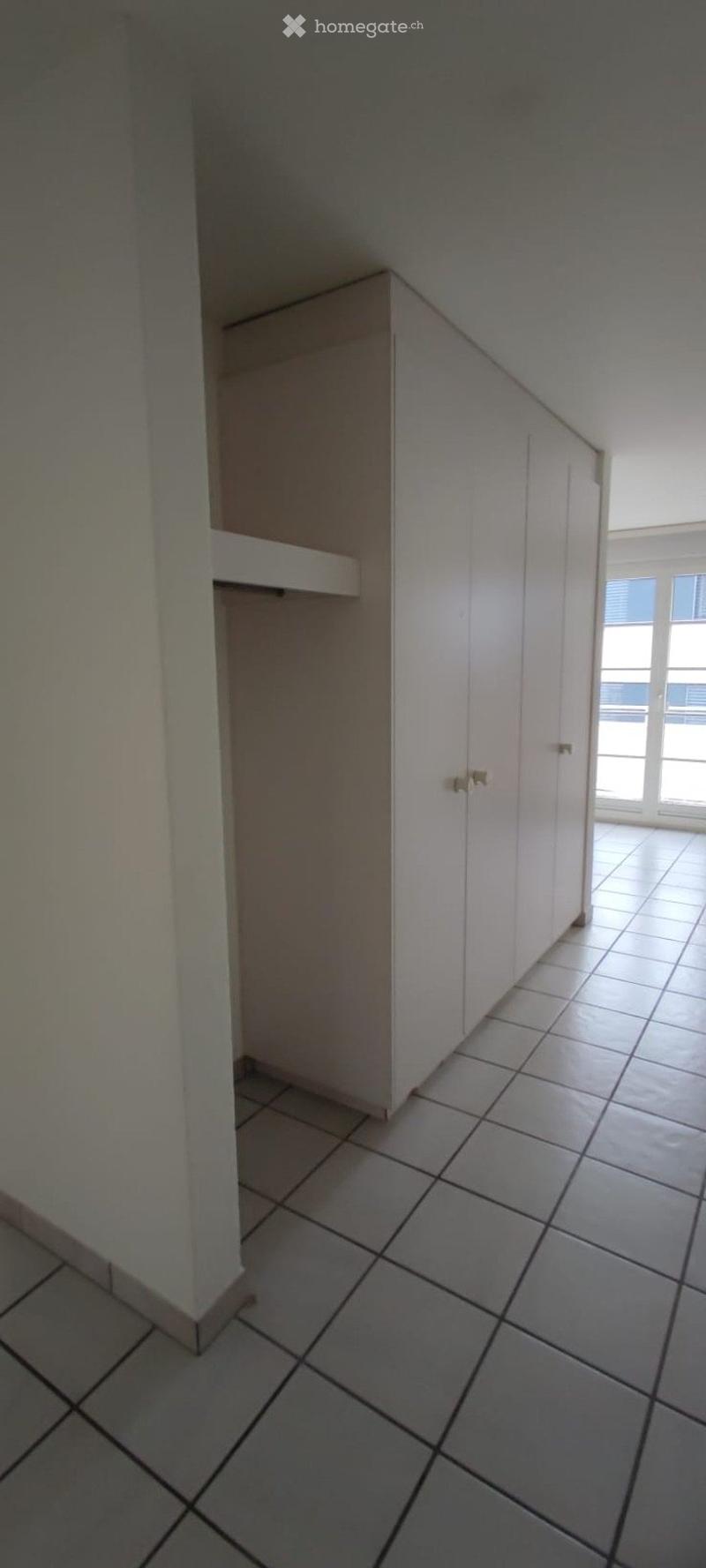 Empty room with tiled floor, white walls, built-in closet with sliding doors, and a window with blinds.
