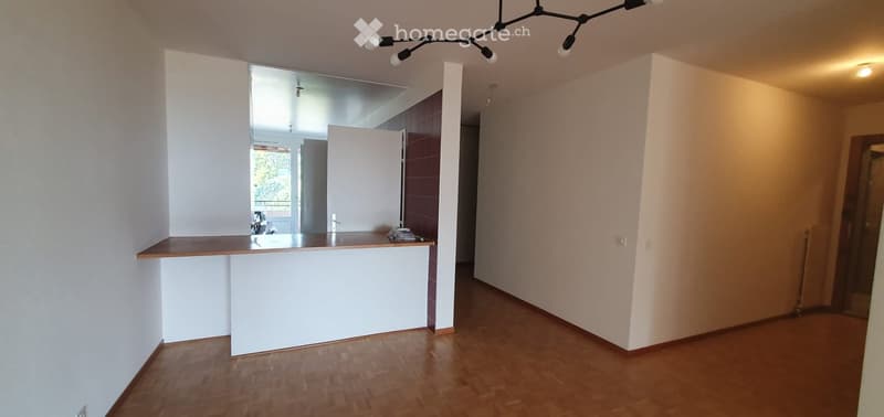 Empty room with wooden flooring, white walls, and a small counter area. No furniture or equipment present.