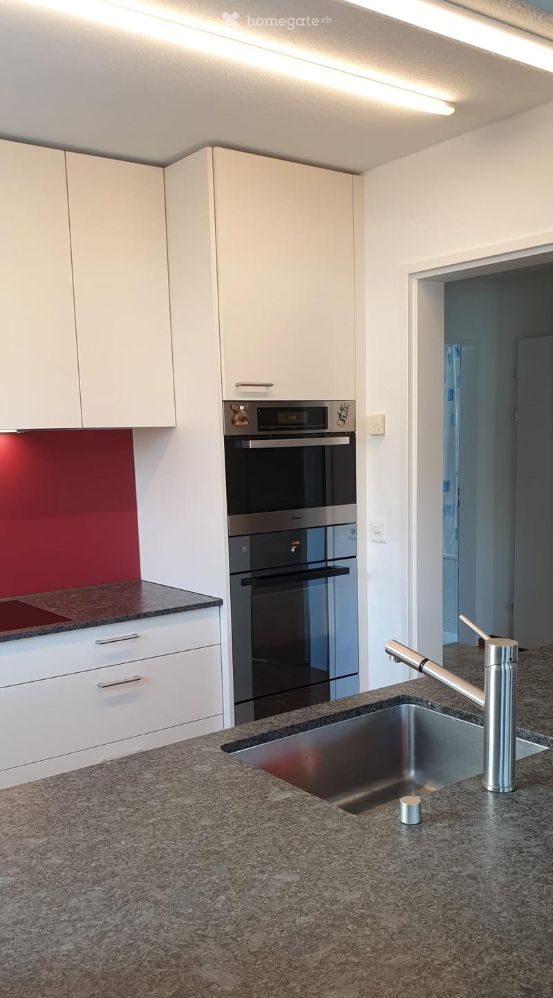 Modern kitchen with white cabinets, granite countertop, stainless steel sink and faucet, and built-in oven.