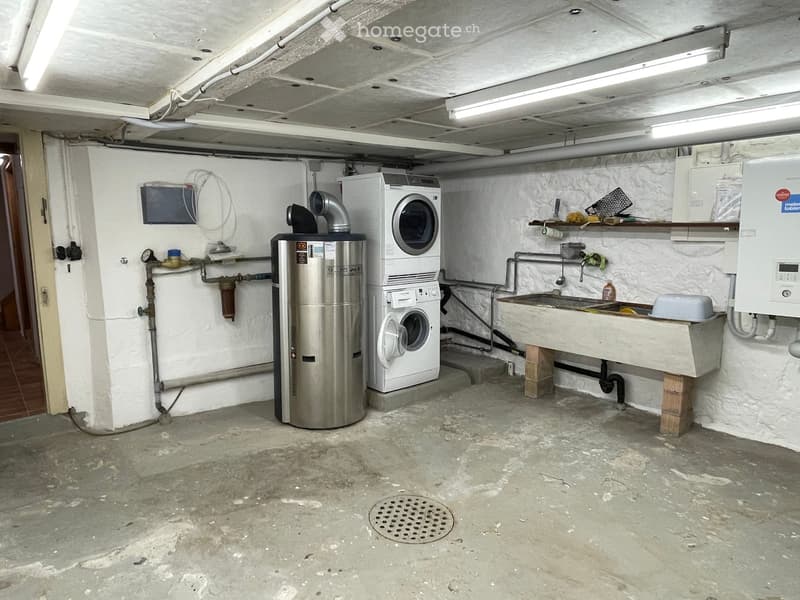 Utility room with a washing machine, water heater, sink, and shelves.