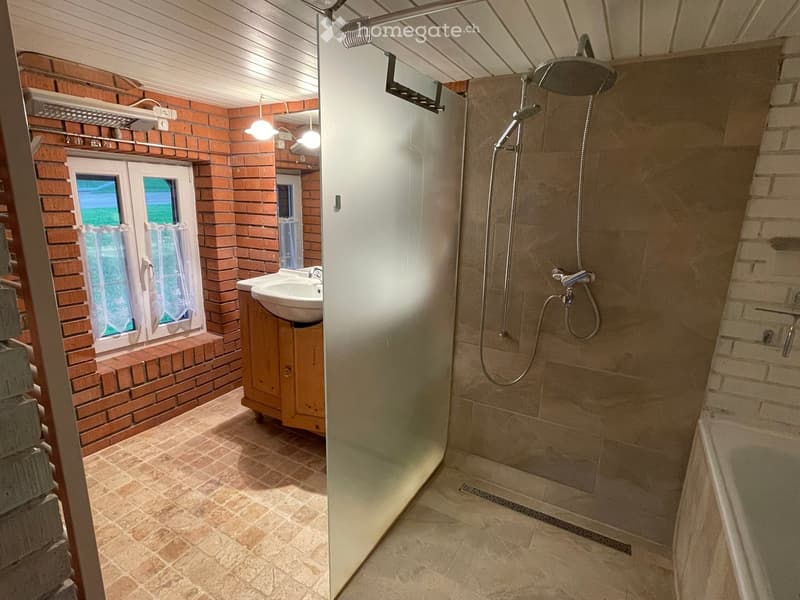 Bathroom with brick walls, tiled floor, shower stall, sink, and bathtub.