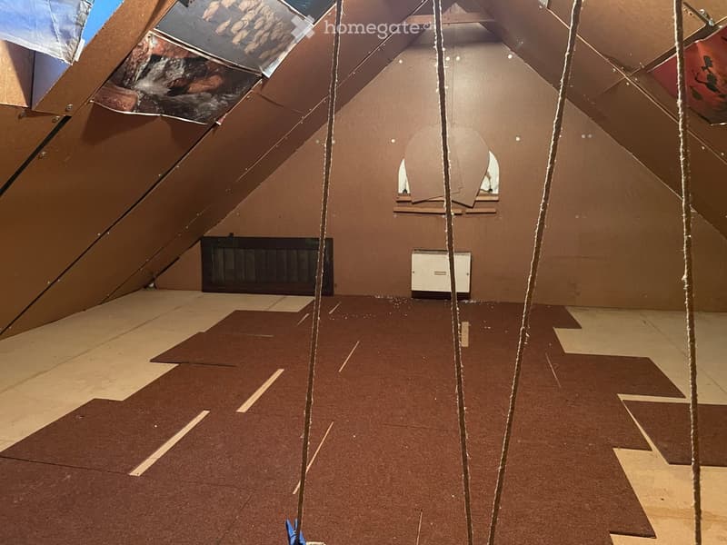 Empty attic space with exposed wooden beams, insulation, and unfinished flooring. No furniture or equipment present.