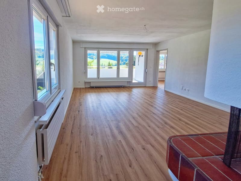 Empty room with wooden flooring, large windows, and a view of the landscape. No furniture or equipment present.