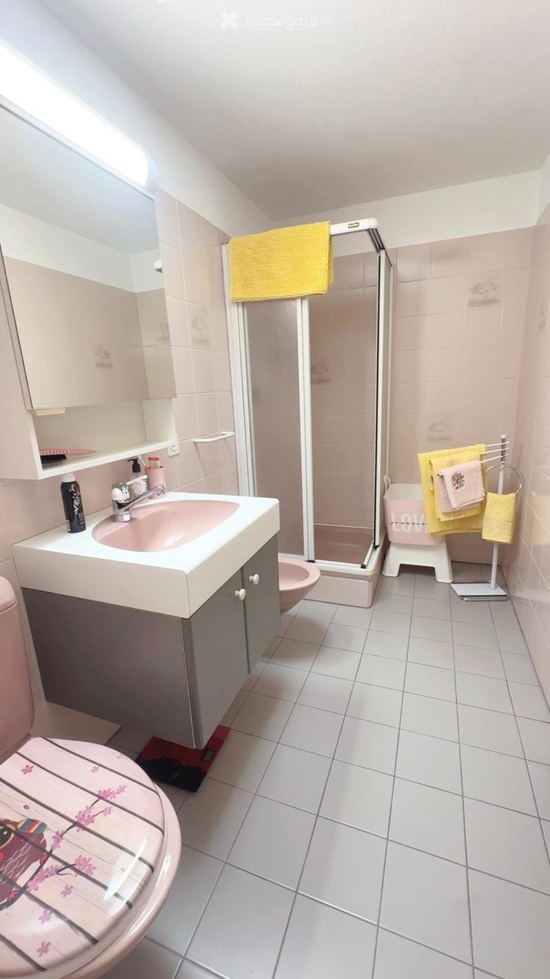 Bathroom with white tiled floor, sink with faucet, mirror, cabinet, toilet, shower, and towel rack with towels.