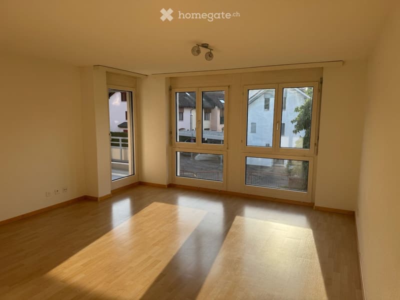 Empty room with wooden flooring, large windows, and natural light. No furniture or equipment present.