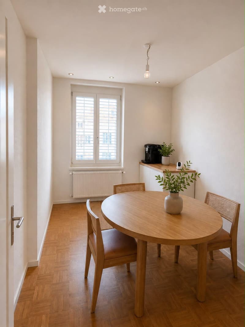 Bright kitchen with wooden flooring, round wooden dining table, four chairs, coffee maker, and potted plants on the counter.