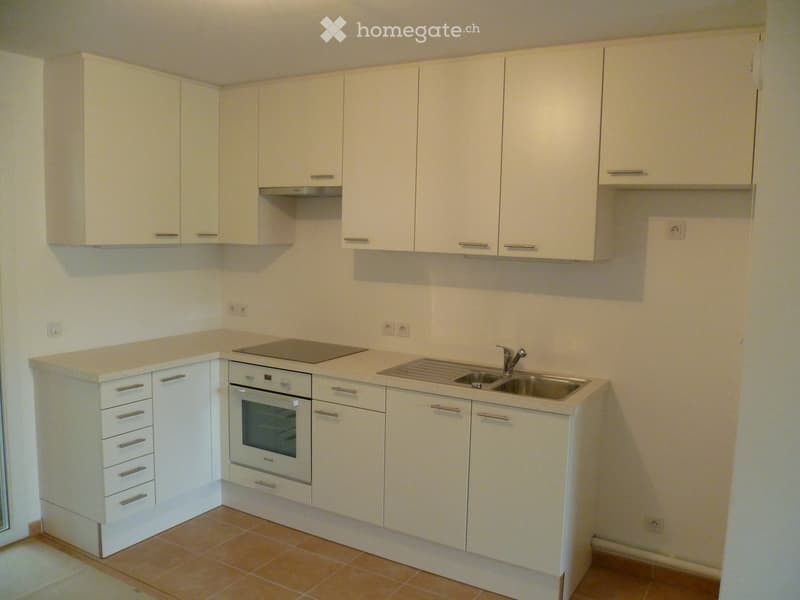 Modern kitchen with white cabinets, stainless steel sink, oven, and countertop.