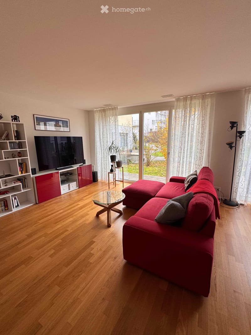 modern open plan living room with glass sliding doors to balcony, red sofa, flat screen TV, bookshelf, coffee table, floor lamps