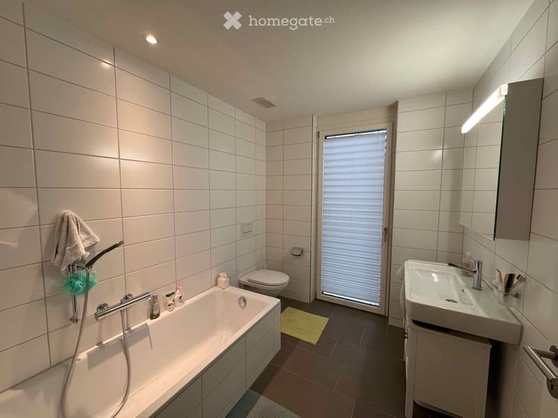 white tiles, bathtub, sink, toilet, glass door, mirror, yellow rug