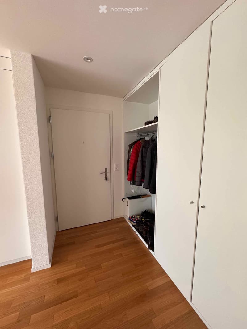 empty closet room, with wooden floor, a closet with shoes underneath, clothes hanging on the hangers