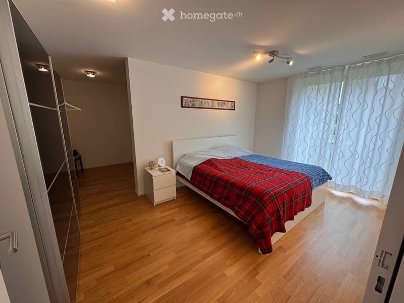 Bedroom with wooden floor, white walls, single bed, nightstand, white curtains, wardrobe, and a picture frame.