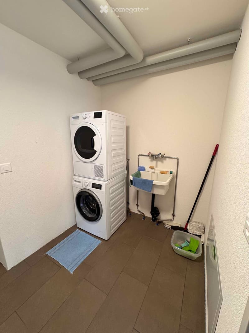 A laundry room with washing machine and dryer on the top and bottom, small sink and cleaning supplies
