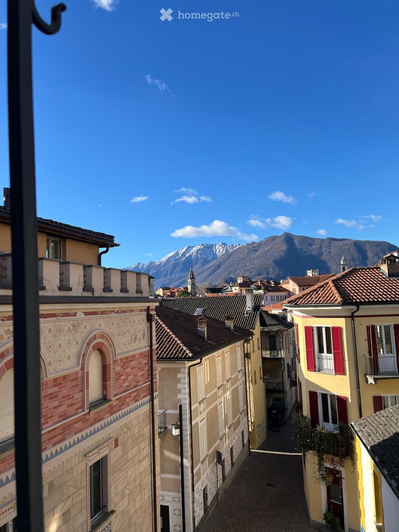 A picturesque narrow street lined with colorful buildings, featuring a scenic mountain view in the background.