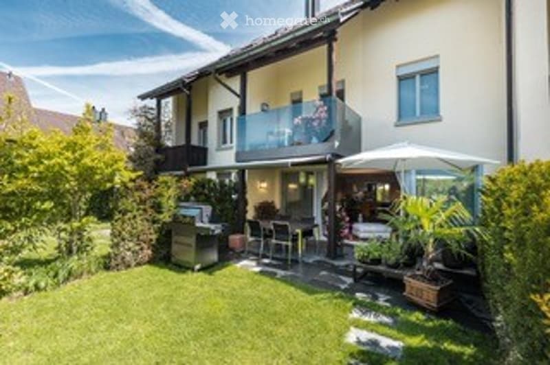 Well-maintained garden area with a patio, outdoor furniture, and a small balcony accessible from the upper floor.
