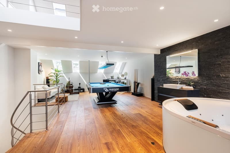 Modern, open-concept space with a pool table, sofa, bathtub, and sink, featuring wooden flooring and large windows.