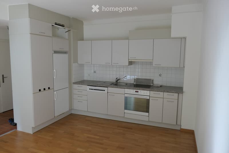 Modern kitchen with white cabinets, a refrigerator, dishwasher, oven, and a sink with a faucet. The countertops are tiled, and the floor is wooden.