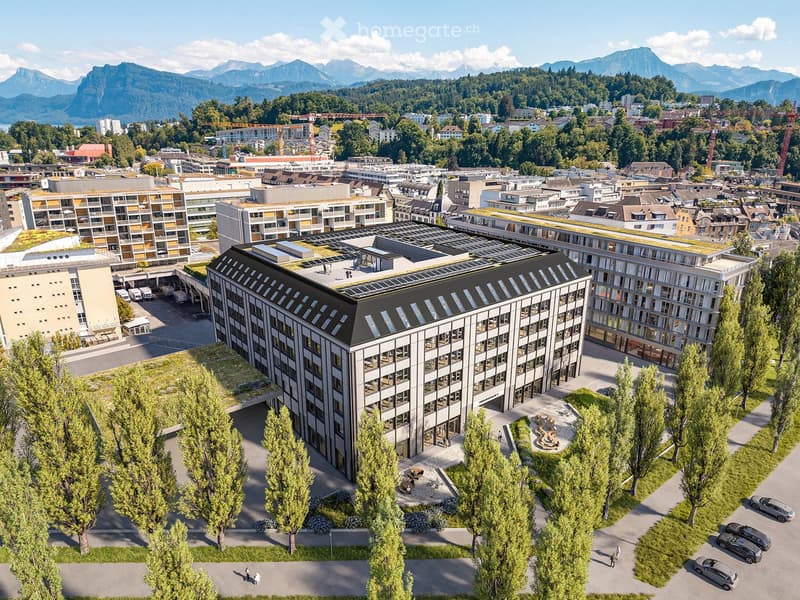 Modern office building with green roofs, large windows, surrounded by green trees and grass, multiple cars parked nearby