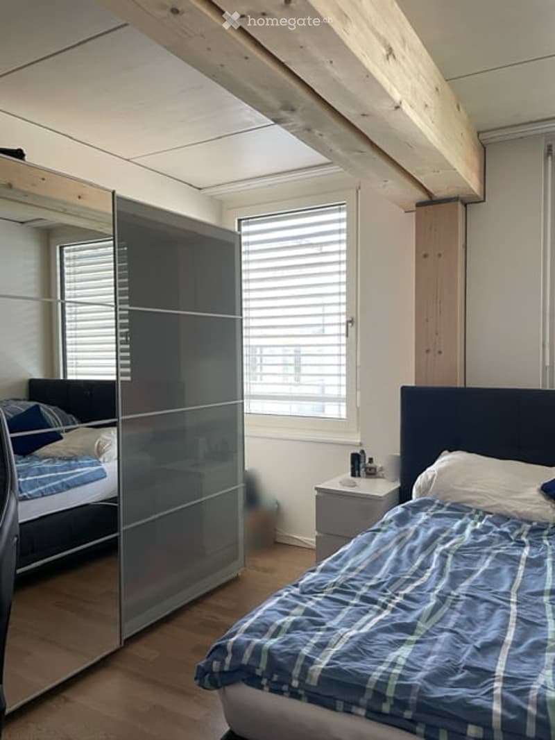 Wooden floor, full size bed, bedside table, glass divider, second bed, large mirror