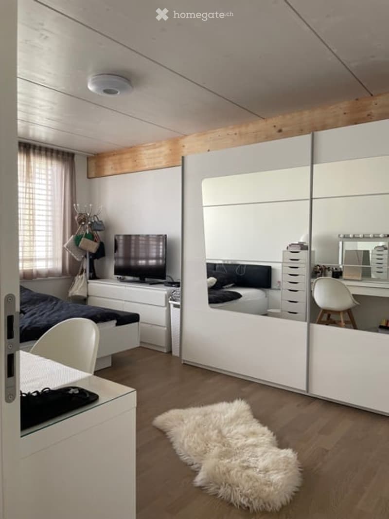 Bedroom with bed, wardrobe, desk, chair, rug, mirror, television, window, wooden wall, wooden ceiling